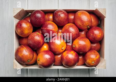 Blood oranges in a wooden box on a white background. Stock Photo