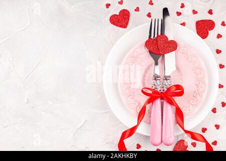 White and Pink Plates with Fork, Knife and Red Ribbon Bow with Decorative Hearts Stock Photo