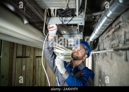 Male Worker Wearing Hard Hat  Connecting Cables Stock Photo