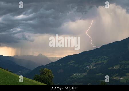 Dramatic sky with thunderstorm and lightning bolt in the mountains at sunset Stock Photo