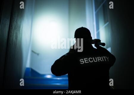 Security Guard Searching On Stairway With Flashlight Stock Photo