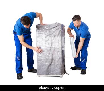 Two Male Movers Wrapping The Home Appliances With Plastic Wrap On White Background Stock Photo