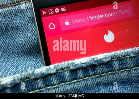 Tinder website displayed on smartphone hidden in jeans pocket Stock Photo