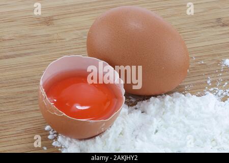 Two eggs and flour on a wood surface Stock Photo