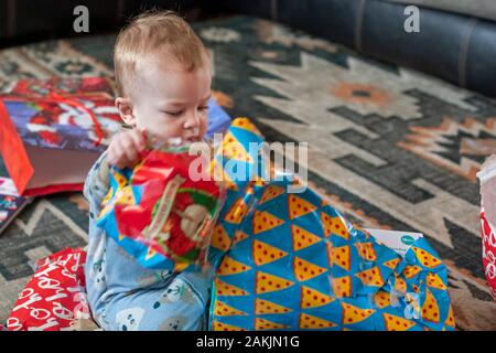 Denver, Colorado - Hendrix Hjermstad, a year and a half old, tears open a present on Christmas morning. Stock Photo