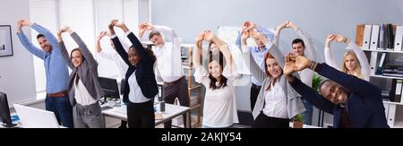 Group Of Smiling Multi-ethnic Young Office Workers Doing Stretching Exercise At Workplace Stock Photo