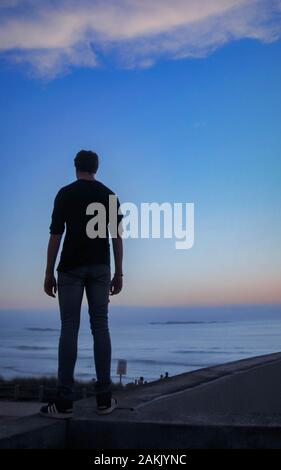 Man In Black Shirt Looks Out Over The Sea Stock Photo