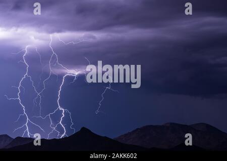 Dramatic lightning bolts strike ahead of a monsoon thunderstorm drifting across the desert southwest of Phoenix, Arizona. Stock Photo