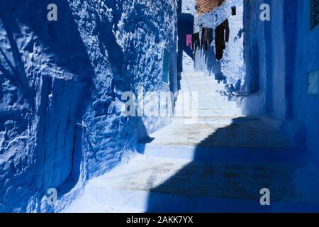 Partially enshadowed flight of stairs and the laundry hanging on clothes line in medina of Chefchaouen (also known as Chaouen), Morocco Stock Photo
