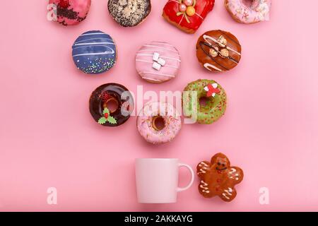 Colorful Donuts with icing and coffe cups on pastel rose background. Sweet donuts. Flat lay Stock Photo