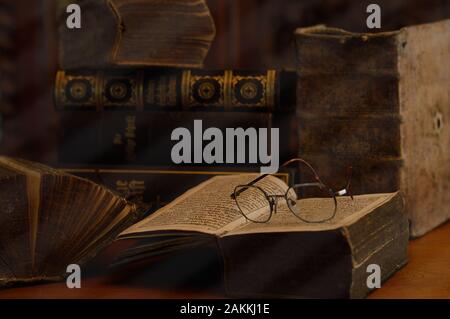 antique books with reading glasses in a dusty room Stock Photo