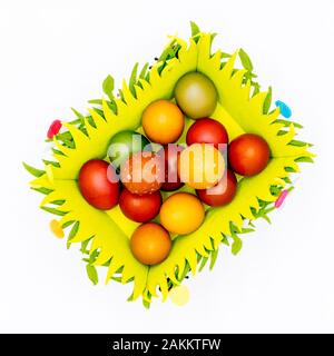 Stash of colourful Easter eggs, wax hand painted in a felt Easter basket on plain, isolated white background, top view Stock Photo