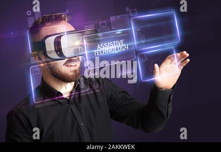 Businessman looking through Virtual Reality glasses with ASSISTIVE TECHNOLOGY inscription, new technology concept Stock Photo