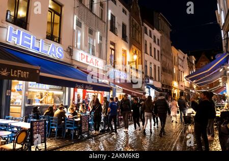 Greek cafes line the street in the historic old town of Brussels Belgium on a rainy late night in the busy, crowded urban center. Stock Photo
