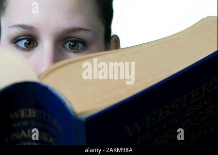 Young female college student reading a very large textbook Stock Photo