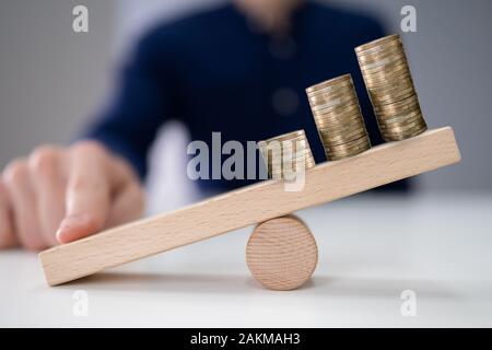 Close-up Of A Businessperson Balancing Increasing Stacked Coins With Finger On Seesaw Stock Photo