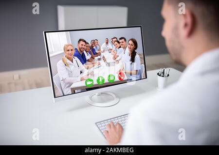 Young Male Doctor Video Chatting On Laptop In Clinic Stock Photo