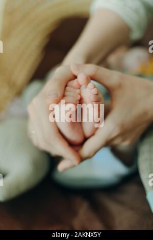 Baby feet in mother hands. Mom and her Child. Happy Family concept. Beautiful conceptual image of Maternity Stock Photo