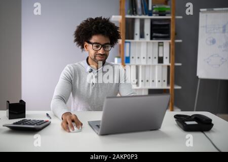 Successful Accountant Calculating Tax At Office Desk Using Laptop Stock Photo