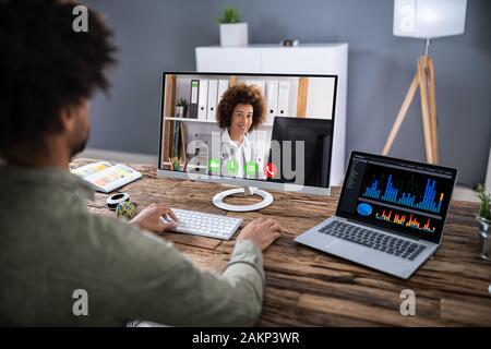Businessman Sitting At A Desk Watching An Online Presentation On The Computer Stock Photo