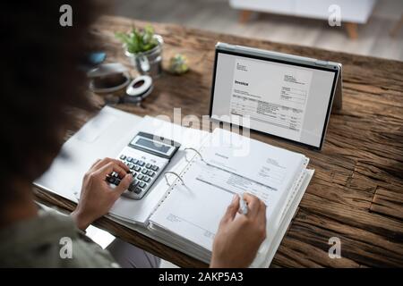 Close-up Of Businessman's Hands Working On Invoice On Laptop At Office Stock Photo