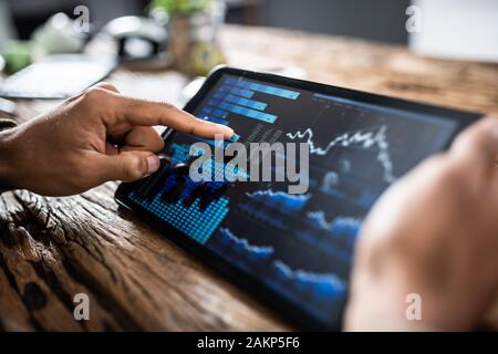 Close-up Of A Businesswoman's Hand Analyzing Graph On Digital Laptop At Workplace Stock Photo