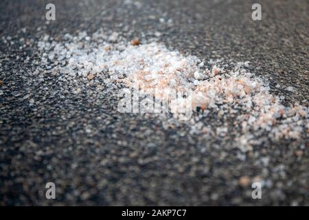 Salt spilled on the pavement. Winter season, slick and dangerous. Nature protection and ecology Stock Photo