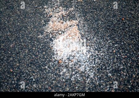 Salt spilled on the pavement. Winter season, slick and dangerous. Nature protection and ecology Stock Photo