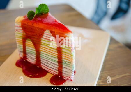 close up of rainbow crepe cake on wooden plate Stock Photo