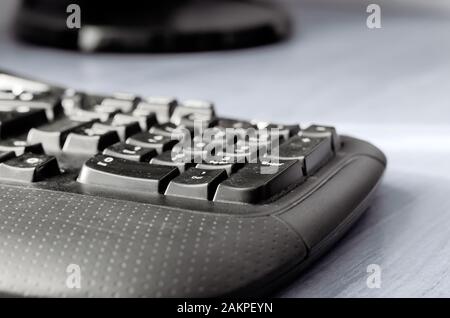 Black computer keyboard on a light gray table. A closeup of a used office keyboard. Eye level shooting. Selective focus. Stock Photo