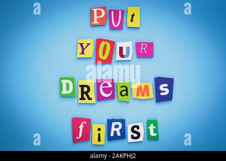 Put your dreams first. Positive thinking concept. Text of cut colorful letters on blue background. Writing on banner, card. Inscription, message on po Stock Photo