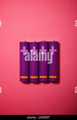 Four small batteries on a pink table. Stock Photo