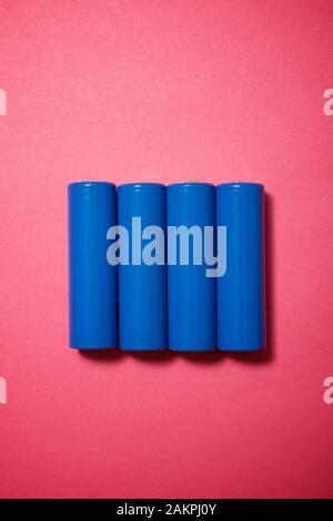 Four small batteries on a pink table. Stock Photo