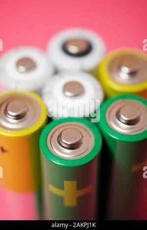 Seven batteries on a pink table. Stock Photo