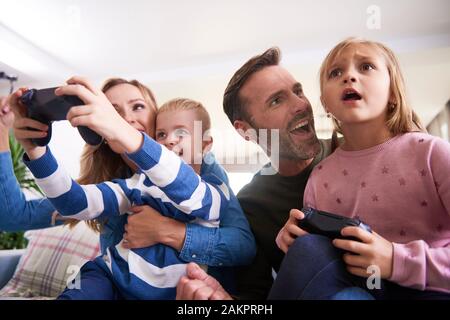 Emotional parents and children playing video game Stock Photo