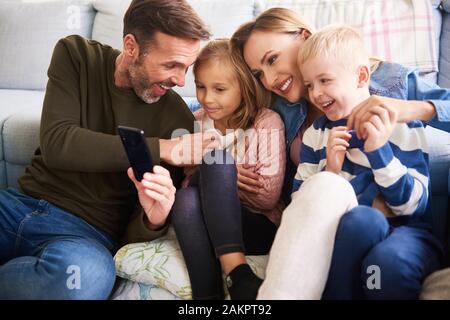 Family using mobile phone in living room Stock Photo