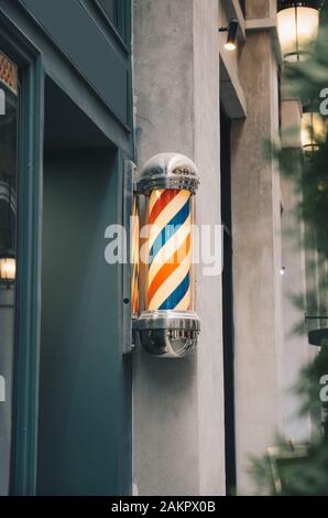 barber pole on grey wall with green wooden barber shop Stock Photo