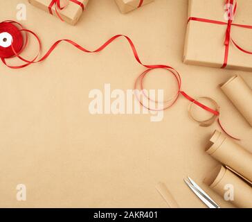 brown kraft paper, packed gift bags and tied with a red ribbon, set of items for making gifts. Package design, copy space Stock Photo