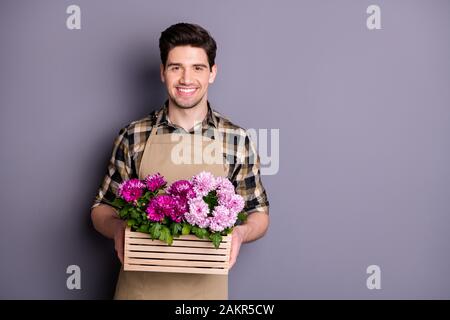 Photo of attractive worker guy holding hands amazing pink flowers growing in pot advising buy fresh flowers without cutting down wear apron plaid Stock Photo