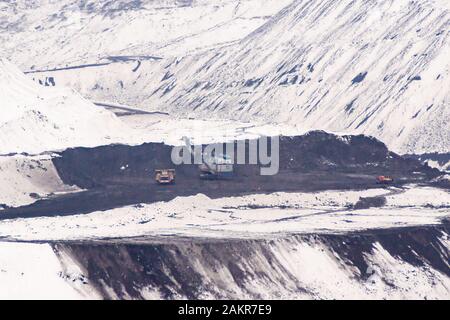 opencast winter mining, working with an excavator and heavy dump trucks, rock removal Stock Photo