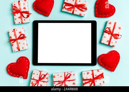 Top view of digital tablet surrounded with gift boxes and hearts on colorful background. Saint Valentine's day. Stock Photo