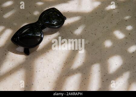Summer composition with sunglasses and palm leaf shadows Stock Photo
