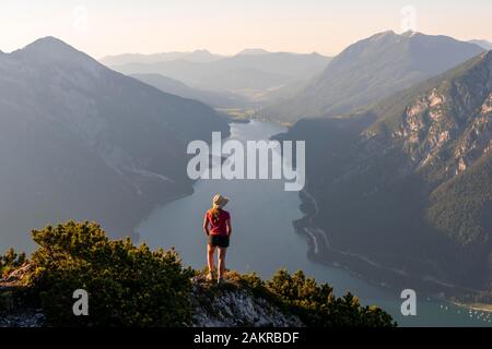 Young woman looking over mountain landscape, view from the mountain Baerenkopf to Lake Achensee, left Seebergspitze and Seekarspitze, right Rofan Stock Photo