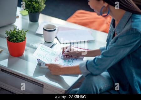 Pleasant creative woman looking at her drawing Stock Photo - Alamy