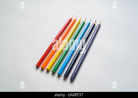 Set of rainbow colored pencils, diagonally positioned on white piece of blank paper Stock Photo