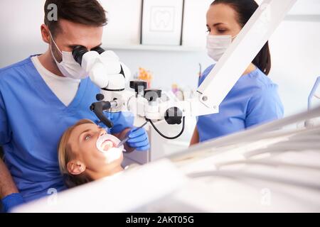 Male dentist looking through dental microscope Stock Photo