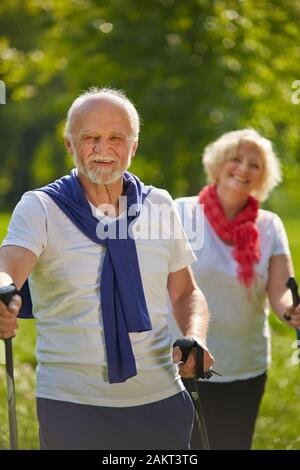 Happy couple seniors on a hike in the forest with trekking poles Stock Photo