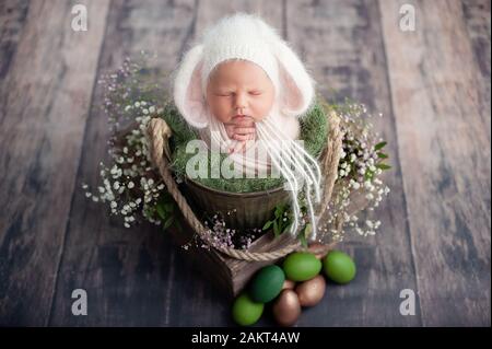 10 day old newborn baby is sleeping in basket. Two week old child. Beginning of life and happy fairy magic childhood concept. Easter bunny. Happy east Stock Photo