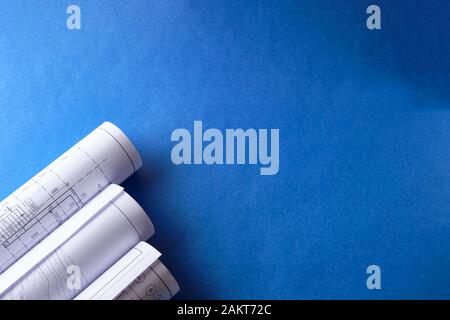 Rolled engineering drawings at blue background with copy space. Stock Photo