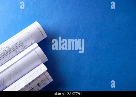 Rolled engineering drawings at blue background with copy space. Stock Photo